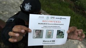Un policía muestra un aviso de recompensa para quien dé informes que permitan recapturar a Joaquín "El Chapo" Guzmán.