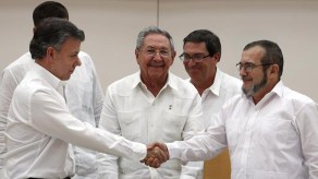 El presidente de Colombia, Juan Manuel Santos, estrecha la mano del lider de las FARC, conocido como Timochenko. Entre ambos, el presidente de Cuba, Raúl Castro.