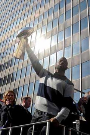 Justin Tuck alza el trofeo de Vince Lombardi que le arrebataran a los Patriotas de Nueva Inglaterra en el Súper Bowl XLVI.