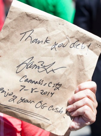 Deb Greene muestra una bolsa de papel con marihuana dentro.