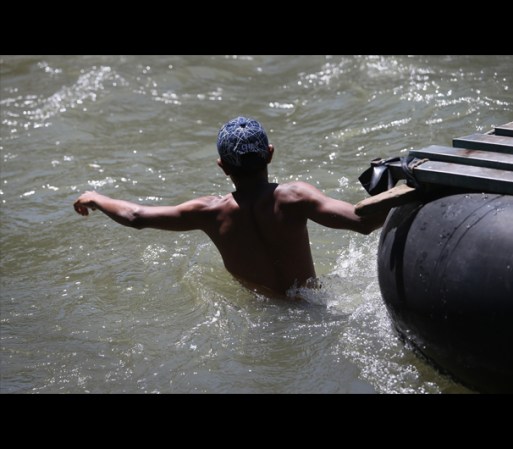 Un hombre opera una balsa improvisada con la cual transporta inmigrantes indocumentados a través del rio Suchiate, en la frontera de México y Guatemala.