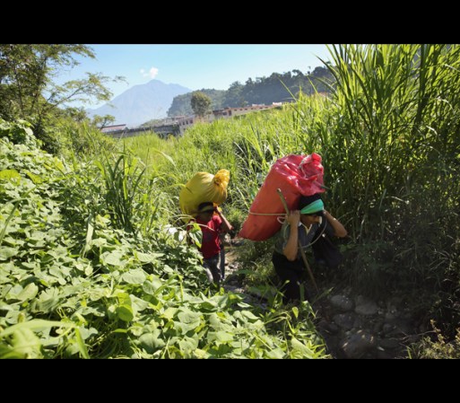 Agricultores Guatemaltecos cargan pesados costales de productos con lo que cruzarán la frontera para venderlos en México.