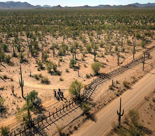 TOHONO O'ODHAM NATION, AZ - DECEMBER 09: A group of young men walk along the Mexican side of the U.S.-Mexico border fence in a remote area of the Sonoran Desert on December 9, 2010 in the Tohono O'odham Reservation, Arizona. Federal agents flying over the group said the men would probably cross the fence after dark to make their trek into the United States. (Photo by John Moore/Getty Images)