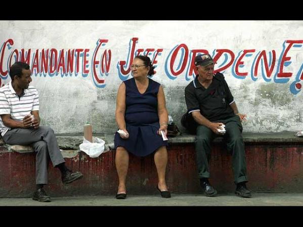Cubanos venden cigarrillos y velas de forma irregular, haciendo caso omiso del cartel a sus espaldas.