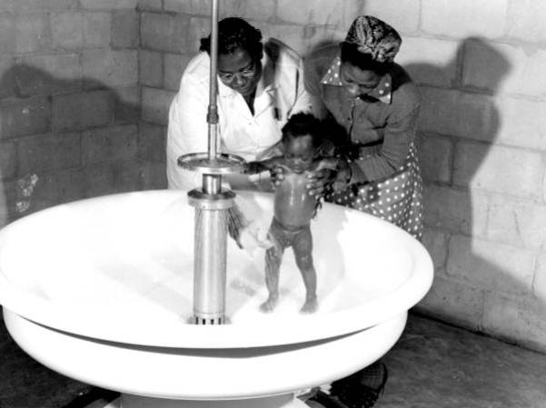Africanos dandole un baño a bebé estadounidense en un campamento de trabajadores - Belle Glade, Florida, 1941.