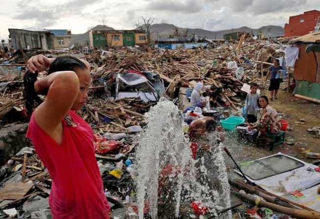 TACLOBAN, PHILIPPINES - NOVEMBER 13: A woman washes amid scenes of devastation in the aftermath of Typhoon Haiyan on November 13, 2013 in Tacloban, Leyte, Philippines. Typhoon Haiyan, packing maximum sustained winds of 195 mph (315 kph), slammed into the southern Philippines and left a trail of destruction in multiple provinces, forcing hundreds of thousands to evacuate and making travel by air and land to hard-hit provinces difficult. Around 10,000 people are feared dead in the strongest typhoon to hit the Philippines this year. (Photo by Kevin Frayer/Getty Images)
