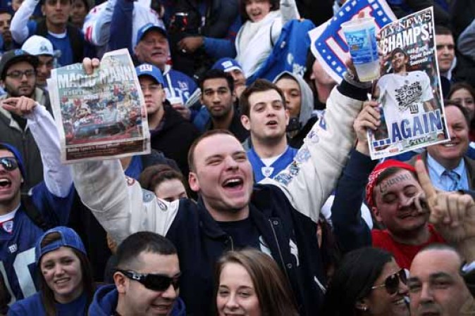 Este fanático alza diarios con las portadas ganadoras del Súper Bowl durante el desfile en Nueva York.