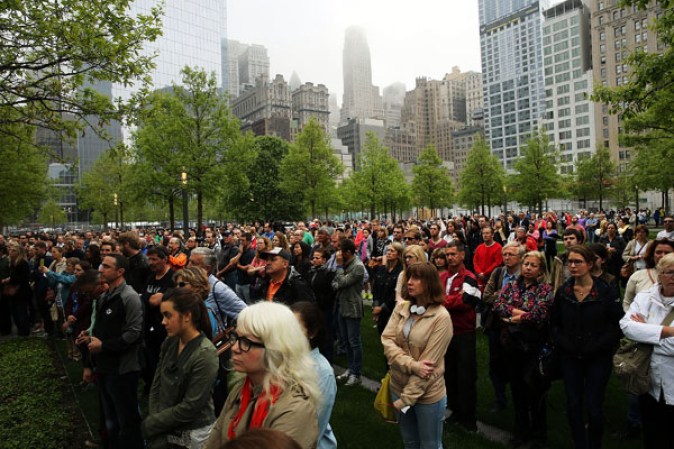 NEW YORK, NY - MAY 15: People watch a live video from the Ground Zero memorial site of the dedication ceremony of the National September 11 Memorial Museum in New York May 15, 2014 in New York City. The museum spans seven stories, mostly underground, and contains artifacts from the attack on the World Trade Center Towers on September 11, 2001 that include the 80 ft high tridents, the so-called "Ground Zero Cross," the destroyed remains of Company 21's New York Fire Department Engine as well as smaller items such as letter that fell from a hijacked plane and posters of missing loved ones projected onto the wall of the museum. The museum will open to the public on May 21. (Photo by Spencer Platt/Getty Images)