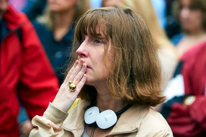 NEW YORK, NY - MAY 15: Lucile Corty, of Paris, France, watches a screen projection of the dedication ceremony for the National September 11 Memorial Museum at ground zero May 15, 2014 in New York City. Corty's friend, Stacey Pool, died in the terrorist attacks of Sept. 11, 2001. The museum spans seven stories, mostly underground, and contains artifacts from the attack on the World Trade Center Towers on September 11, 2001 that include the 80-foot high tridents, the so-called "Ground Zero Cross," the destroyed remains of Company 21's New York Fire Department Engine as well as smaller items such as letter that fell from a hijacked plane and posters of missing loved ones projected onto the wall of the museum. The museum will open to the public on May 21. (Photo by James Keivom-Pool/Getty Images)