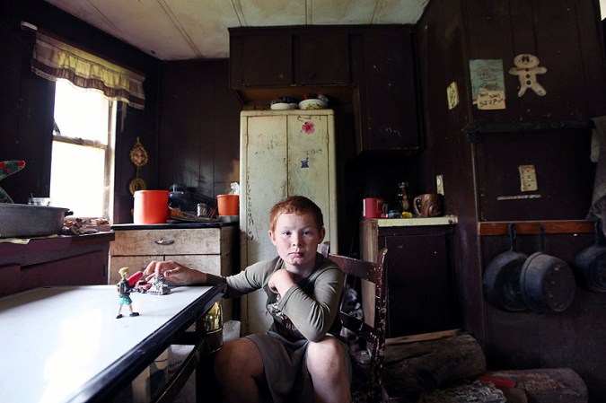 OWSLEY COUNTY, KY - APRIL 21: Mose Noble's nephew Johnny Noble, 9, sits in Mose's trailer during a visit on April 21, 2012 in Owsley County, Kentucky. Johnny visits his uncle from time to time. Mose Noble is a former chimney sweeper who no longer works but volunteers cleaning graveyards. His trailer has no electricity or running water but he receives governmental and neighborly assistance. Daniel Boone once camped in the Appalachian mountain hamlet of Owsley County which remains mostly populated by descendants of settlers to this day. The 2010 U.S. Census listed Owsley County as having the lowest median household income in the country outside of Puerto Rico, with 41.5% of residents living below the poverty line. Familial and community bonds run deep, with a populace that shares a collective historical and cultural legacy uncommon in most parts of the country. However, the community of around 5,000 struggles with a lack of jobs due to the decline in coal, tobacco and lumber industries along with health issues including drug addiction without effective treatment. (Photo by Mario Tama/Getty Images)