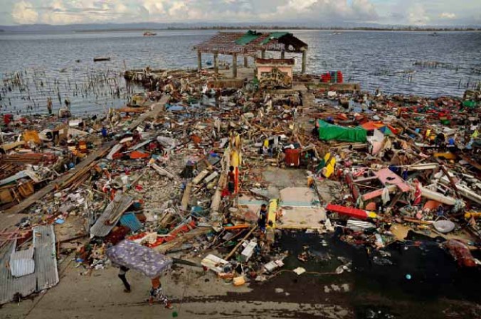 TACLOBAN, PHILIPPINES - NOVEMBER 13: Two men carry a mattress amid scenes of devastation in the aftermath of Typhoon Haiyan on November 13, 2013 in Tacloban, Leyte, Philippines. Typhoon Haiyan, packing maximum sustained winds of 195 mph (315 kph), slammed into the southern Philippines and left a trail of destruction in multiple provinces, forcing hundreds of thousands to evacuate and making travel by air and land to hard-hit provinces difficult. Around 10,000 people are feared dead in the strongest typhoon to hit the Philippines this year. (Photo by Kevin Frayer/Getty Images)