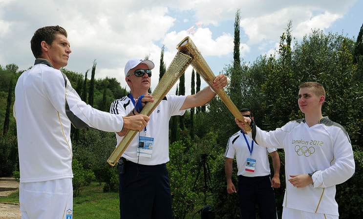 ATHENS, GREECE - MAY 10: Alex Loukas from Britain lights the London 2012 Olympic Torch from Spyros Gianniotis of Greece during the Lighting Ceremony of the Olympic Flame at Ancient Olympia on May 10, 2012 in Olympia, Greece. (Photo by Jamie McDonald/Getty Images)