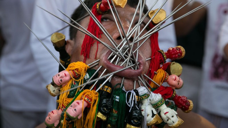 OCTUBRE 10, 2013 – Los hombres en Tailandia se perforan la cara en un festival vegetariano.