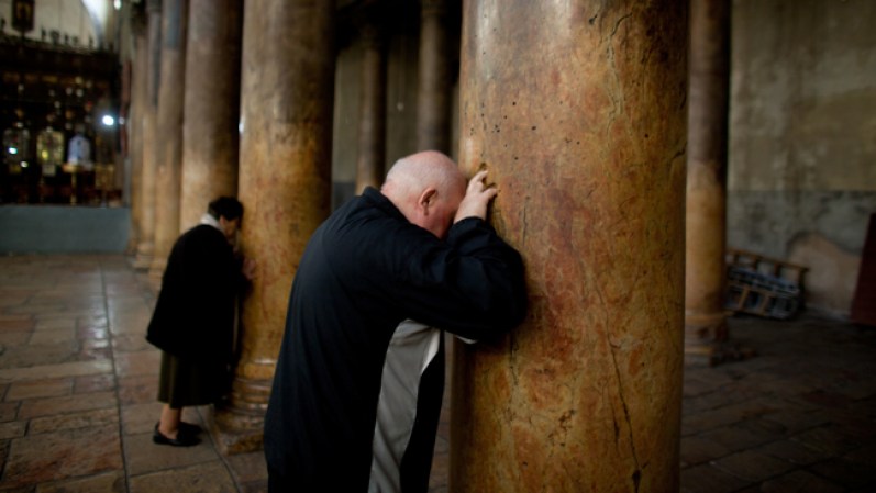 Peregrinos que visitan la iglesia colocan sus dedos en los agujeros en forma de cruz en las antiguas columnas.