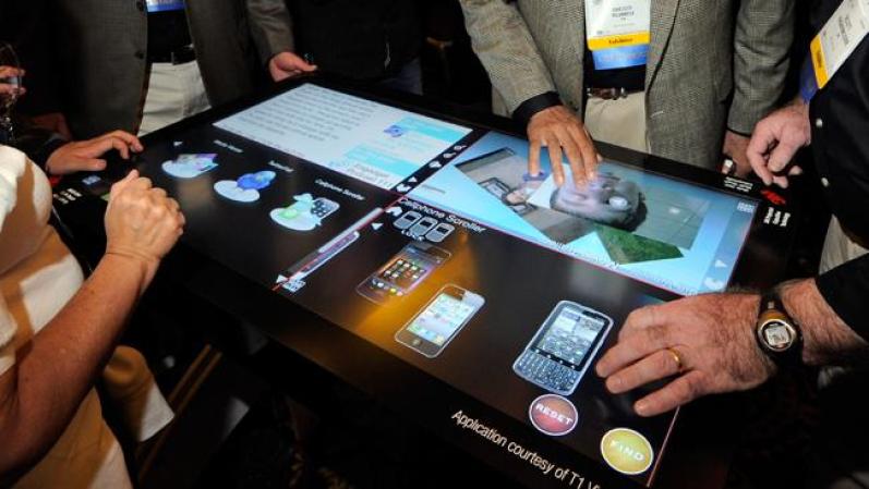Los visitantes prueban la pantalla del 3M Touch Systems, de 46 pulgadas. Reconoce hasta 20 toques de mano a la misma vez.