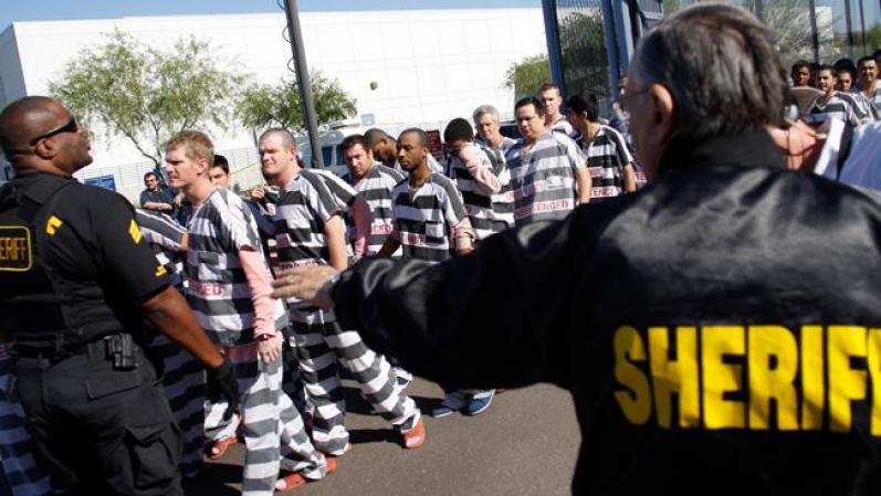 PHOENIX, AZ - APRIL 17: Inmates walk as they are moved after being ordered by Maricopa County Sheriff Officer Joe Arpaio (R), looking on, to be placed into new housing to open up new beds for maximum security inmates on April 17, 2009 in Phoenix, Arizona. Arpaio has been facing criticism from Hispanic activists and lawmakers, alleging that Arpaio's crackdown methods on illegal immigrants involve racial profiling. (Photo by Joshua Lott/Getty Images) *** Local Caption *** Joe Arpaio
