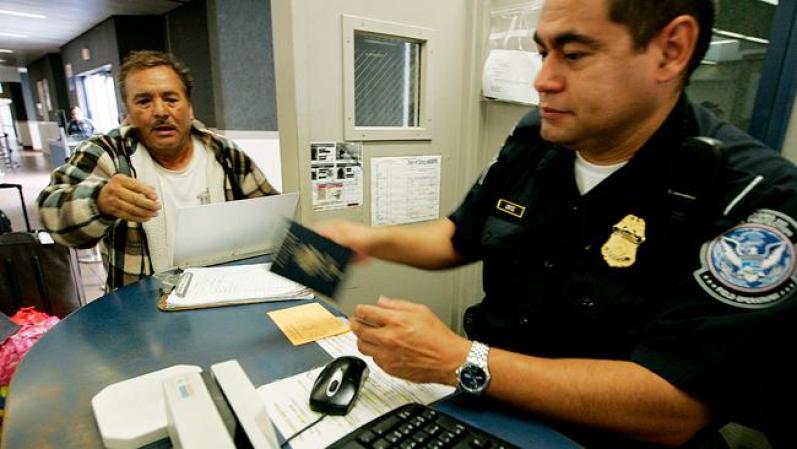 Un oficial de Inmigración chequea el pasaporte de un inmigrante en un puesto de frontera.