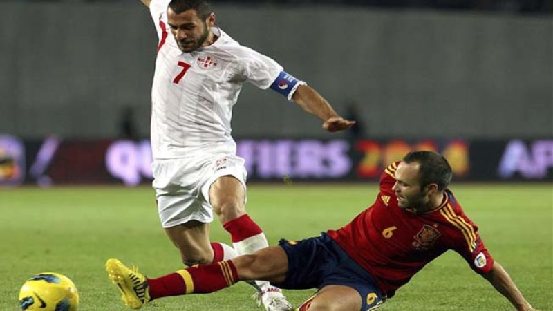 El centrocampista español Andrés Iniesta (d) lucha por el balón con el georgiano Jaba Kankava (i) durante el partido clasificatorio para el Mundial Brasil 2014 jugado en el estadio Borís Paichadze de Tiflis.
