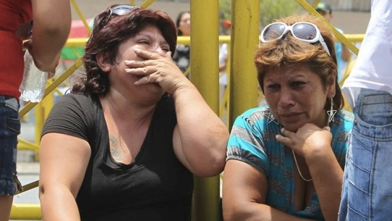 Dos mujeres lloran a las afueras de un centro de rehabilitación para alcohólicos y drogadictos en Lima, donde un incendió dejó menos 26 personas muertas.