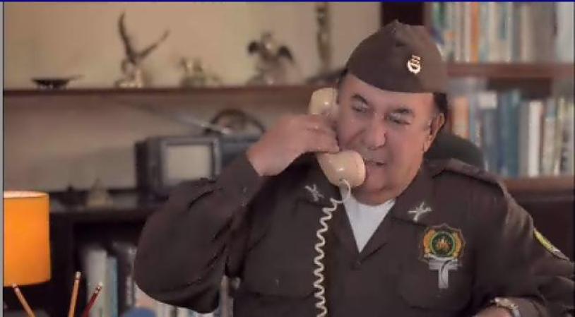 El Coronel recibe la llamada de su superior pidiéndole que se apresure con el operativo, pero él hace tiempo para permitir que Escobar huya.