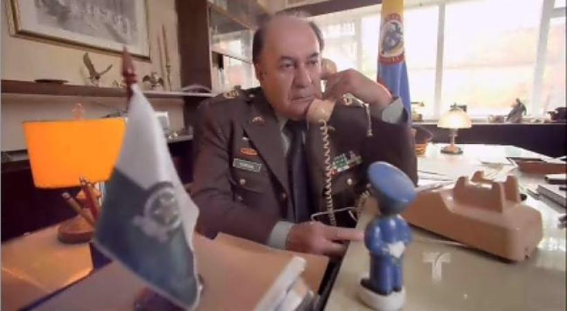 El Coronel le llama a Escobar y le dice que le tiene que entregar a al menos a uno de sus socios.