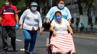Tres mujeres transitan en San Salvador con mascarillas.