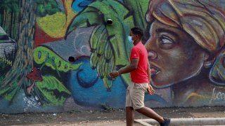 Un joven con tapabocas camina frente a un mural en Tegucigalpa (Honduras)