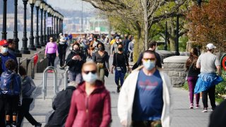 In this April 25, 2020, file photo, a large crowd of people enjoy the weather at Hudson River Park in New York City despite a stay at home order in place during coronavirus pandemic.