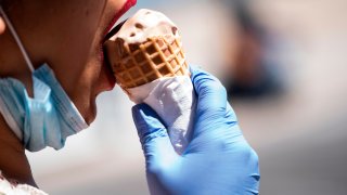 A woman wears gloves as she eats an ice cream cone on the boardwalk during the Memorial Day holiday weekend amid the coronavirus pandemic on May 23, 2020 in Ocean City, Maryland. - The beach front destination has lifted its COVID-19 related beach and boardwalk restrictions May 9 and lodging restrictions May 14. The state of Maryland moved from a stay-at-home order to safe-at-home order May 15. (Photo by Alex Edelman / AFP) (Photo by ALEX EDELMAN/AFP via Getty Images)