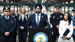 New Jersey Attorney General Gurbur Grewal stands at a podium and is flanked by police officers.