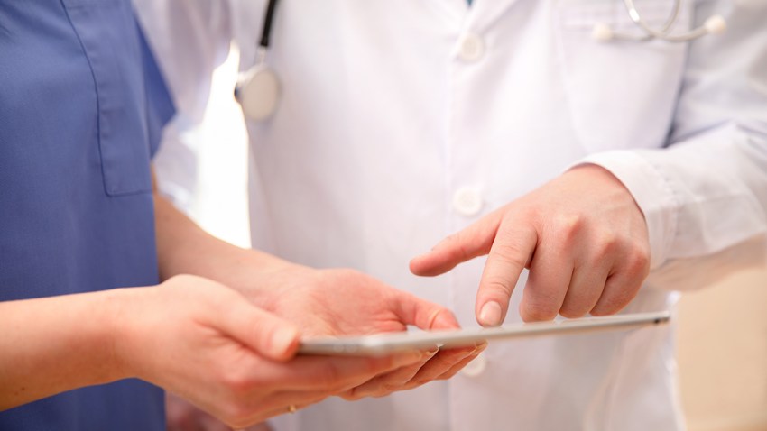 Doctor and nurse discussing patients tests at tablet computer in