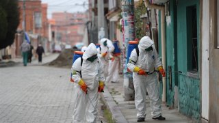 Trabajadores de aseo de la ciudad de El Alto (Bolivia), realizan hoy la fumigación de las fachadas de las casas y calles durante la emergencia sanitaria para evitar la propagación del coronavirus. En Bolivia ya son catorce fallecidos y 194 casos confirmados por COVID-19.