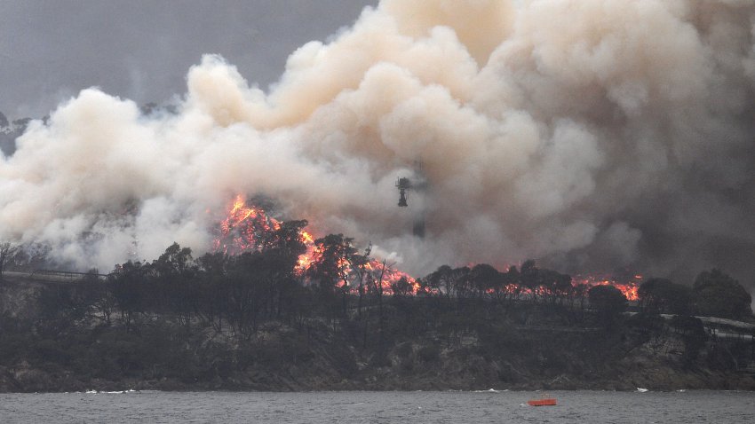 Smoke raises to the sky as a woodchip mill burns in Eden, in Australia’s New South Wales state on January 6, 2020.