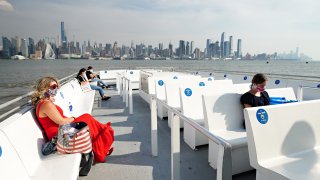 Passengers sit socially distanced on the deck of a NY Waterway ferry