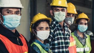 Factory workers with face masks to protect against an outbreak of coronavirus or COVID-19.