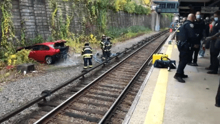 Officials work to remove a sedan that fell near the tracks