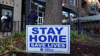 A sign along the sidewalk in an area lined with bars and restaurants in the Wicker Park neighborhood encourages people to stay home