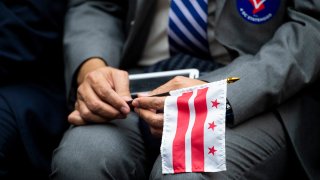 FILE - A Washington, D.C. flag being held during a House Oversight and Reform Committee hearing on D.C. statehood, Feb. 11, 2020.