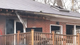 The exterior of a brick home shows charring from a fire