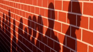 Shadows of marine recruits against a brick wall.