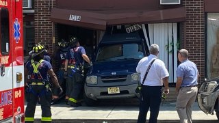 Firefighters inspect a driving school in Asbury Park where a driver backed into the front of the business.
