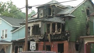 The exterior of a row home is charred, with part of the roof falling, after a fatal fire in Hamilton Township, New Jersey.