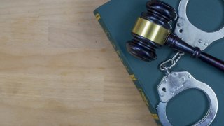 Gavel And Handcuffs On The Law Book Over The Wooden Table Background