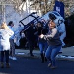 Multiple people stand around and run away as a helicopter crashes to the ground.
