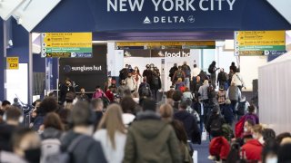 Travelers walk through Terminal C of LaGuardia Airport in New York City
