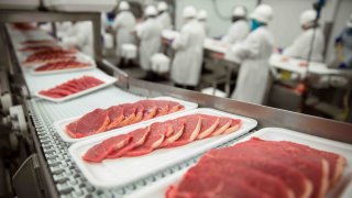 Rebanadas de chuletas de carne delgadas en una cinta transportadora para empaquetar en la planta industrial de la fábrica de carne.