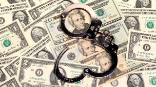 handcuffs sitting on top of US paper currency