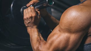 Bodybuilder preparing a barbell on a power rack in gym.