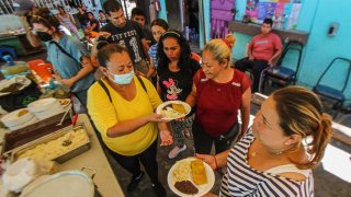 Fila de migrantes que esperan alimentos