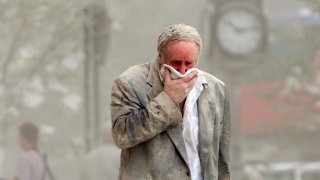This Sept. 11, 2001, file photo, shows Edward Fine covering his mouth as he walks through the debris after the collapse of one of the World Trade Center Towers in New York.